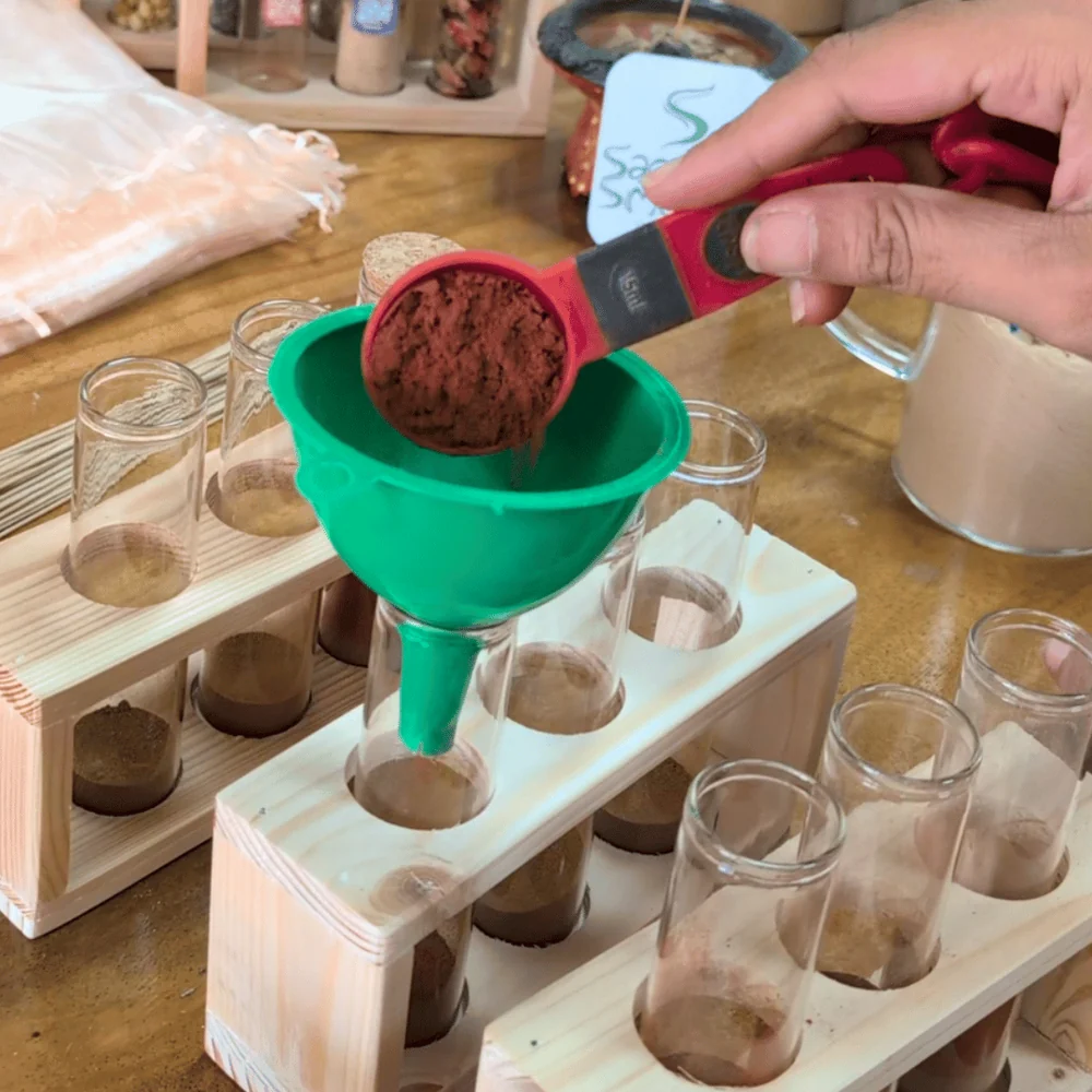 Incense powder being funneled into a glass vial for a DIY kit