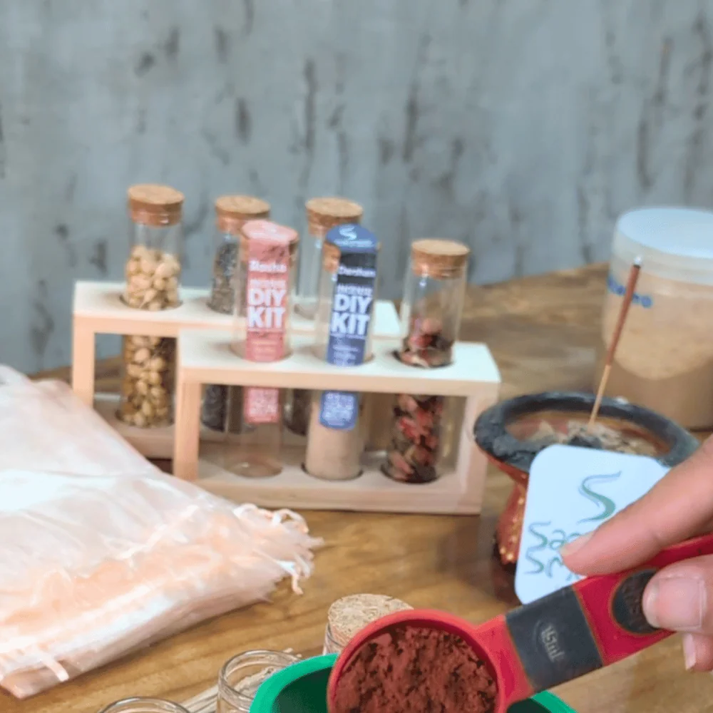 Red incense powder being measured beside DIY incense kits and raw materials