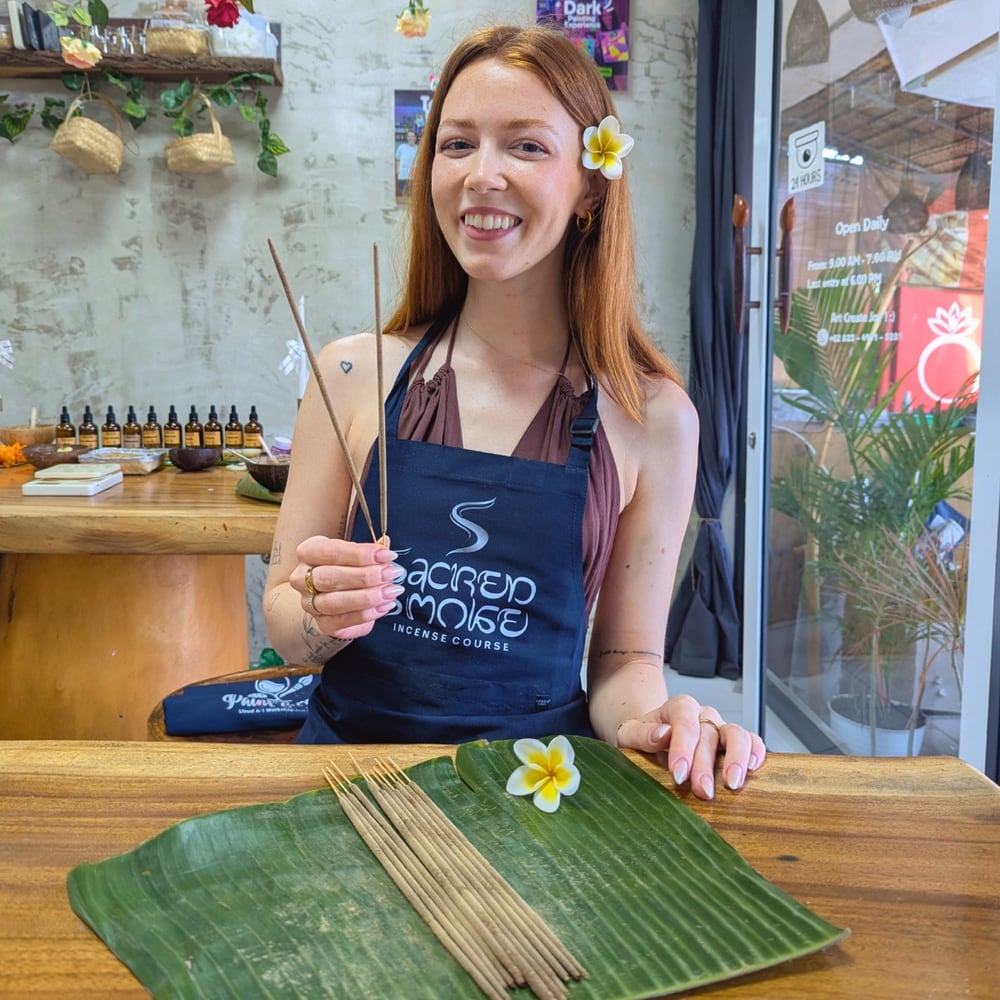 Workshop guest smiling while holding handmade incense sticks