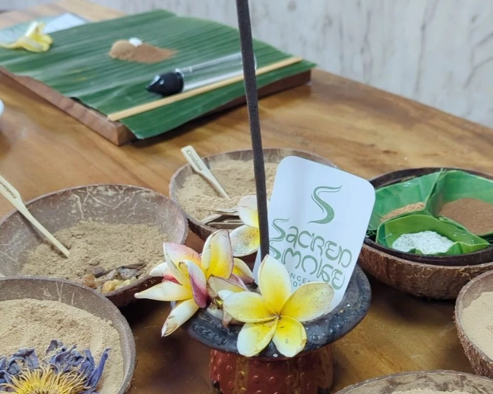 Botanical powders and flowers surrounding incense in the atelier