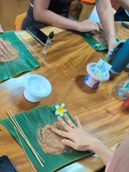 Hands working with incense materials on banana leaves