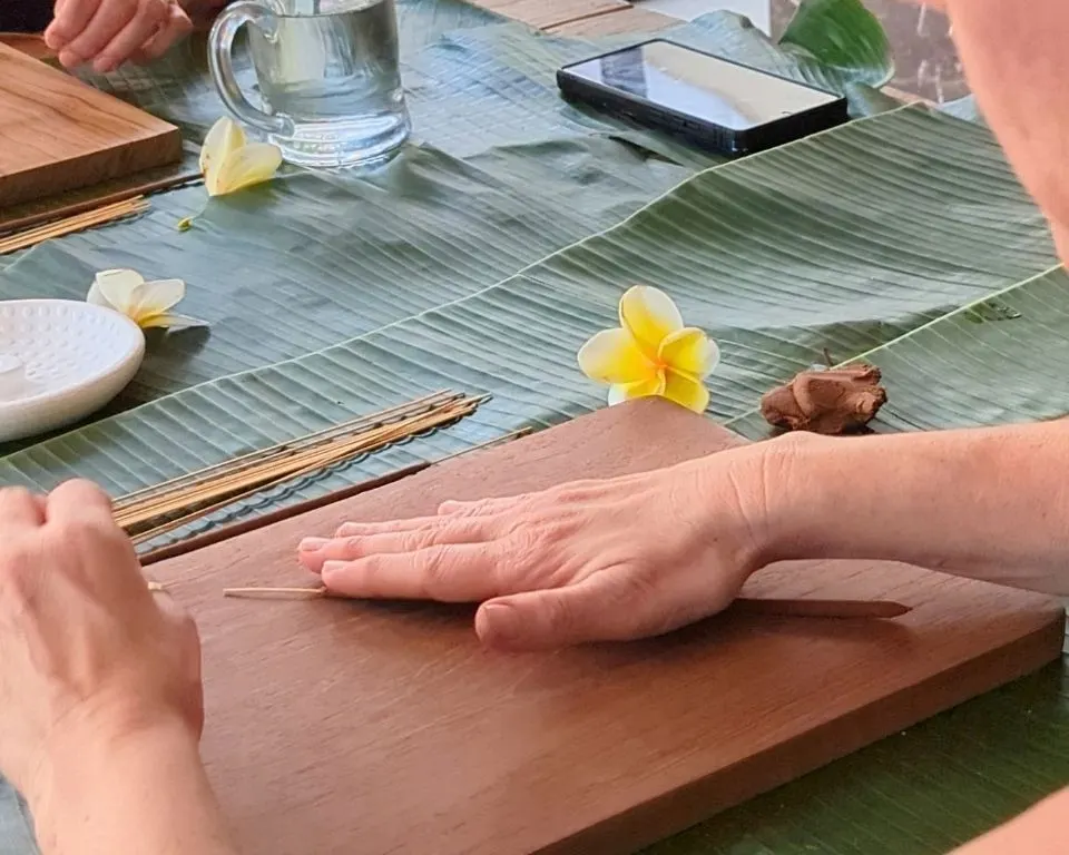 Hands rolling incense onto a bamboo stick