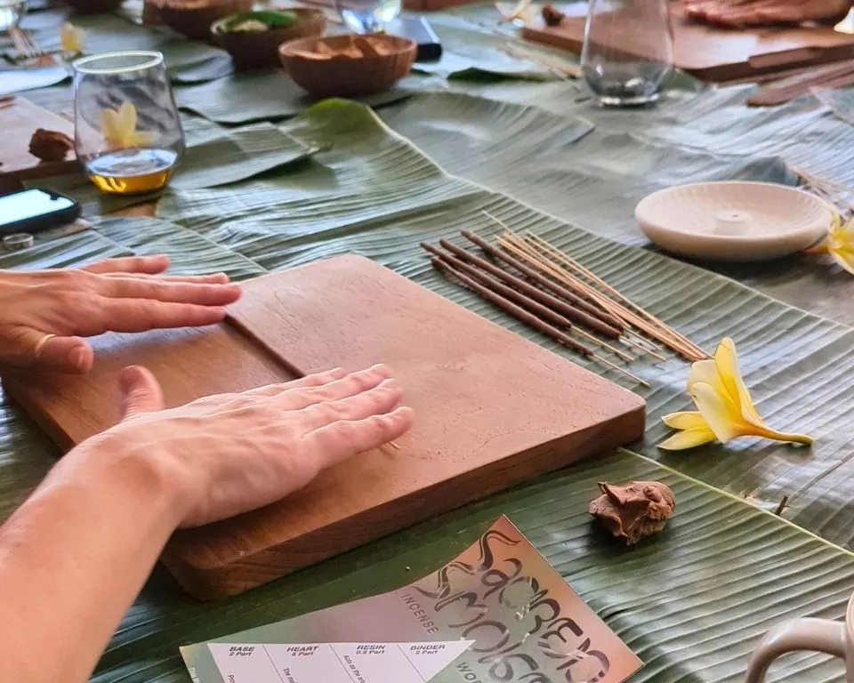 Palm rolling incense beside a formula card